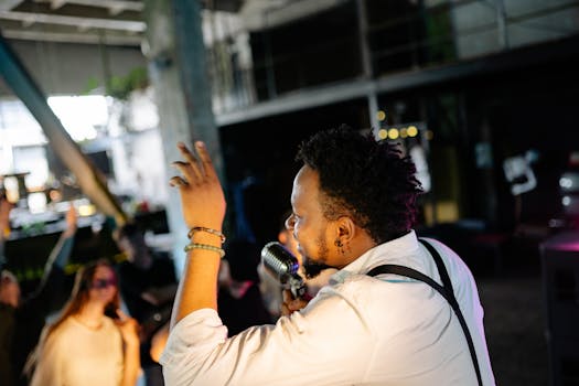 A male musician passionately performing on stage with a vibrant audience.