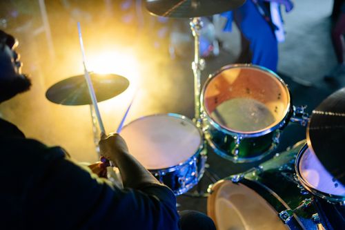 Free Energetic drummer performs live under vibrant stage lighting, capturing the essence of live music. Stock Photo
