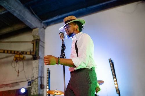 Free Male singer with a hat performs passionately with vintage microphone indoors. Stock Photo