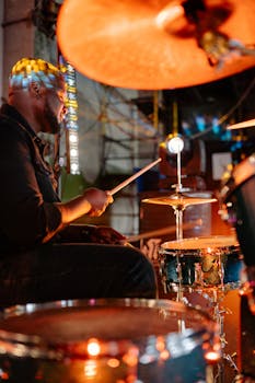 A vibrant image of a drummer playing passionately during a live indoor concert.