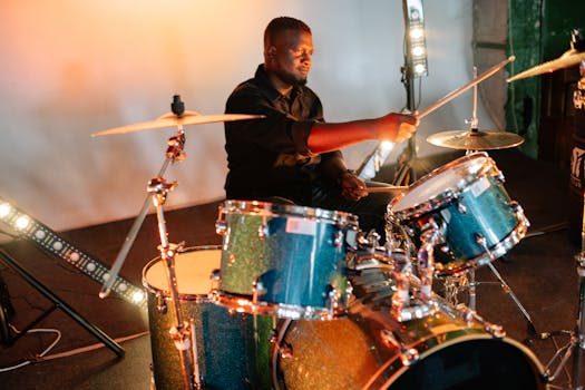 A talented musician playing drums on stage with vibrant lighting and a dynamic setup.