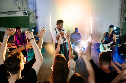 People Putting Hands Up While Dancing in Front of Musicians on Stage