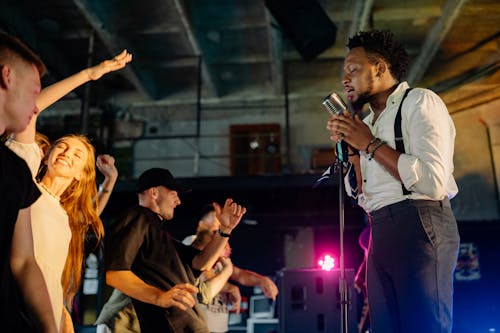 Man in White Shirt Singing on Stage in Front of People