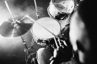 Grayscale Photo of Person Playing Drums
