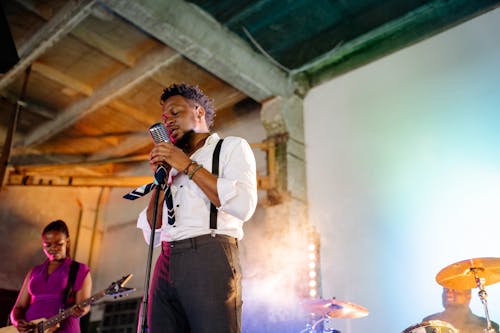 Man in White Dress Shirt Singing on Stage