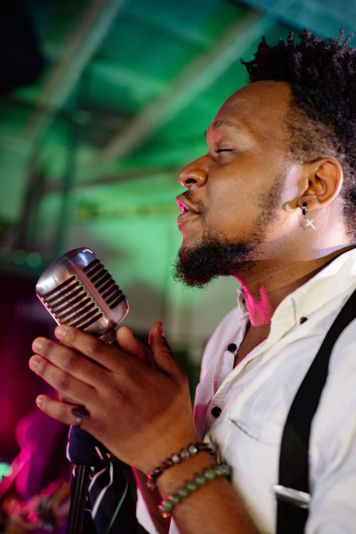 Free Passionate male singer with eyes closed performing music indoors with vintage microphone. Stock Photo