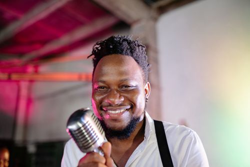 Free A joyful male singer with facial hair holding a vintage microphone indoors. Stock Photo