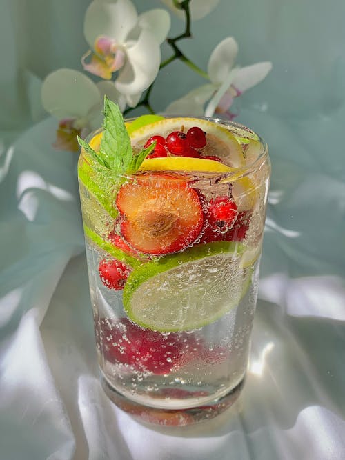 Free A Glass of Bubbly Citrus Drink with Red Berries and Mint Leaves Stock Photo