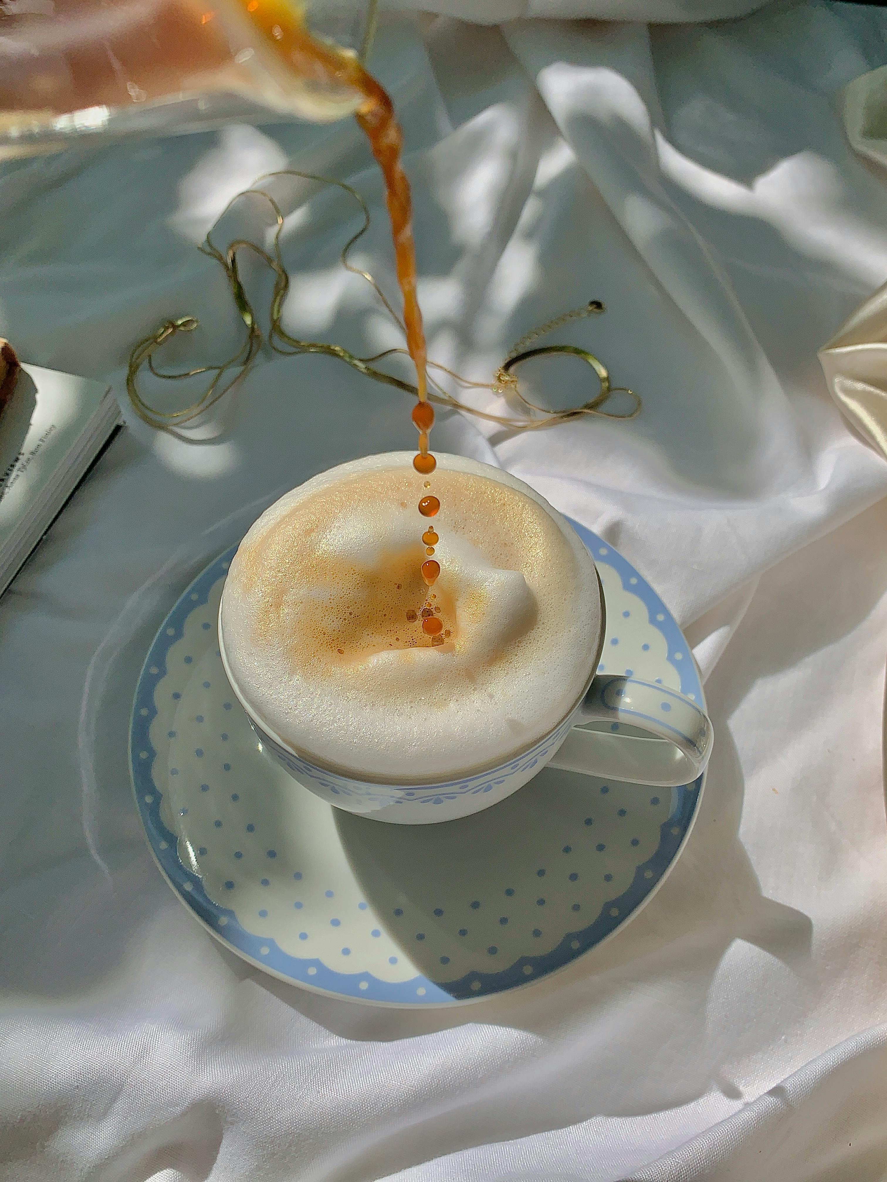 a person pouring a brown liquid on a frothy drink