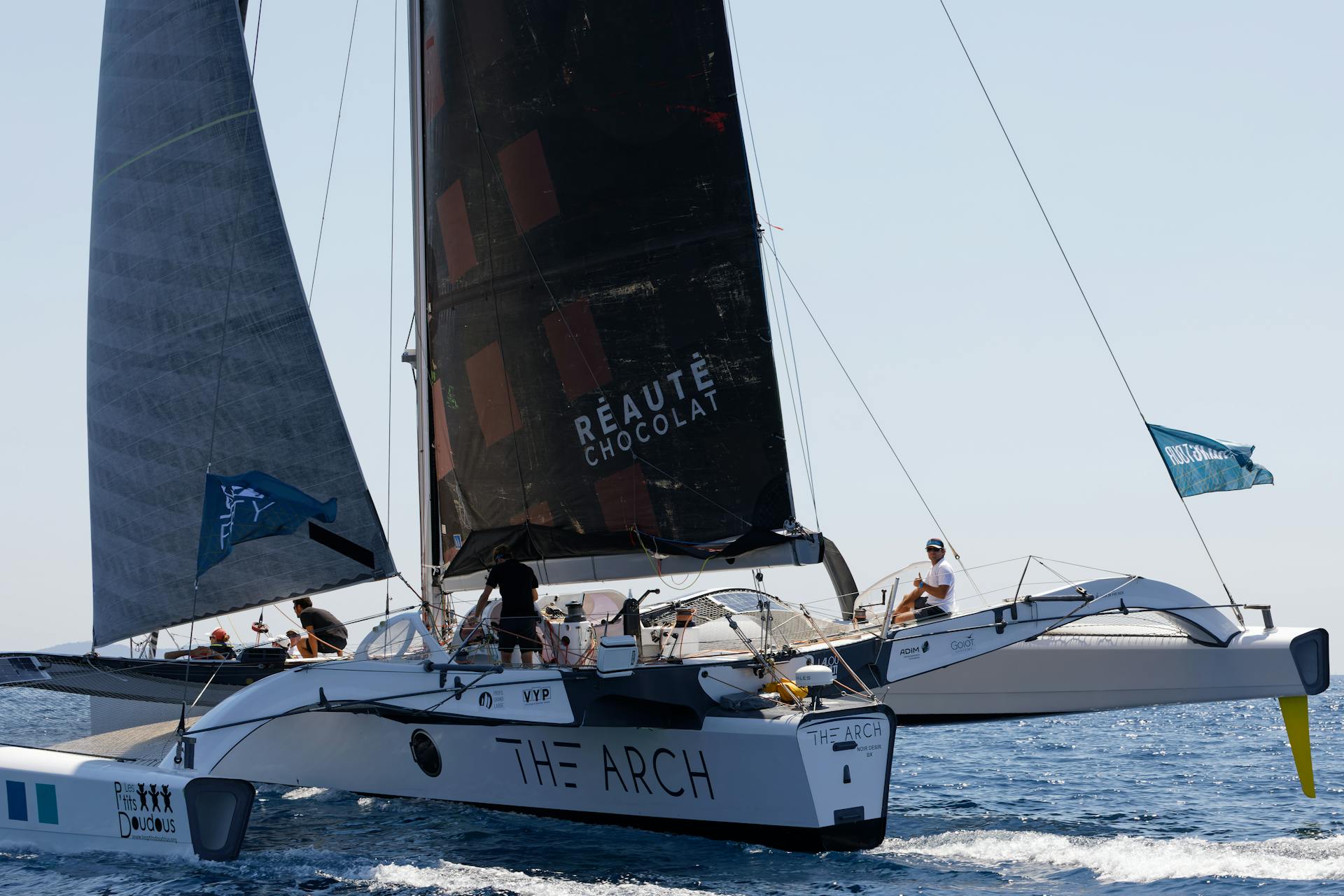 Catamaran sailing with crew in open water, capturing adventure and recreation.