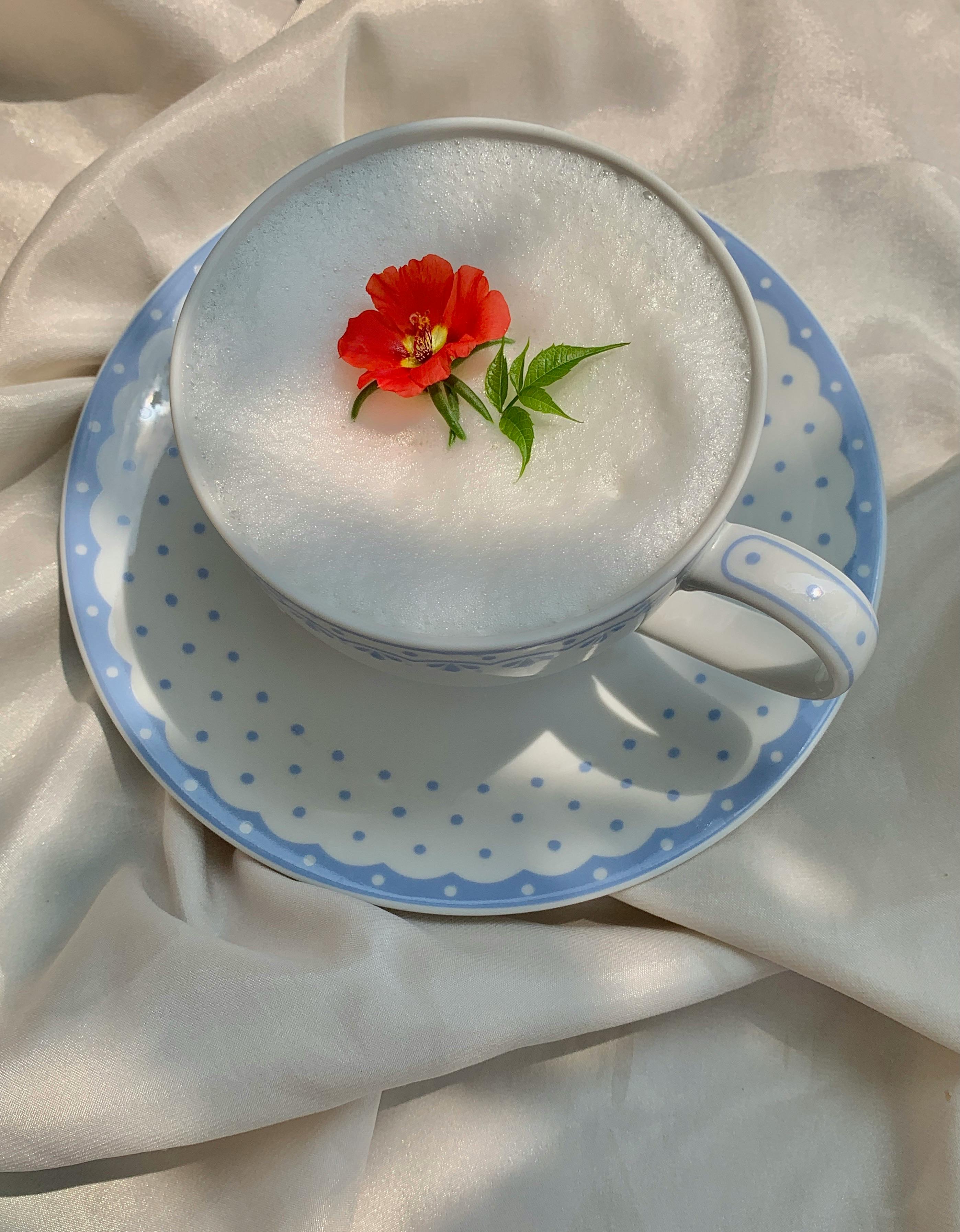 a cup of foamy drink with flower