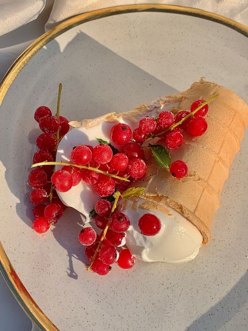 A delicious flatlay of red currant topped ice cream in a waffle cone, perfect for a summer treat.