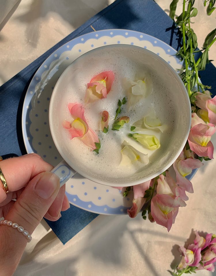 A Person Holding A Cup Of Floral Tea