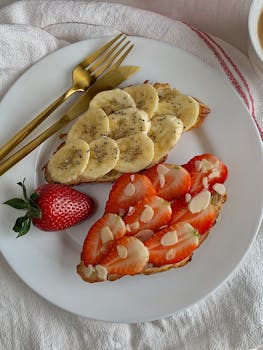 Delicious fruit and nut topped toasts with strawberries and bananas on a white plate.