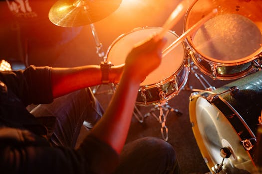 Dynamic shot of a drummer playing under warm stage lighting, showcasing energy and rhythm.