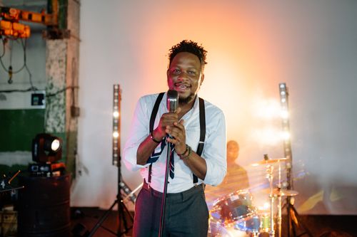 Free A charismatic male singer performing passionately on stage with vibrant lights. Stock Photo