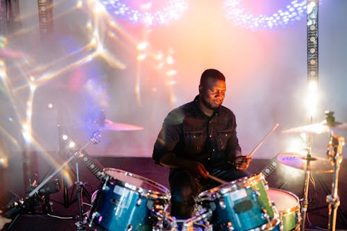 Photograph of a Man in a Black Jacket Playing the Drums