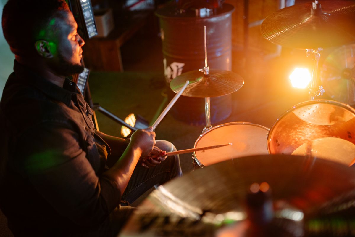 Drummer performing under stage lighting