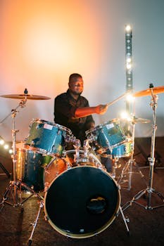 A drummer passionately plays his drum set under vibrant stage lights, creating dynamic music vibes.