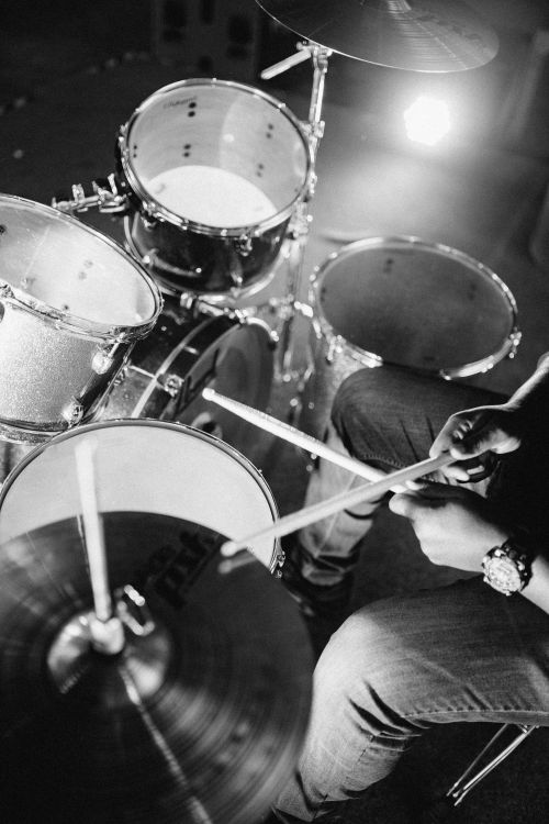 Free A musician playing a drum kit in a black and white photo. Captures the energy and focus of the performance. Stock Photo