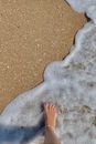A Person Walking Barefooted on the Shore with Seafoam