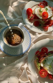 Enjoy a delicious breakfast of avocado toast with fresh tomatoes and a cup of coffee.