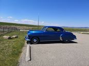 A Blue Classic Car Parked on a Concrete Parking Area