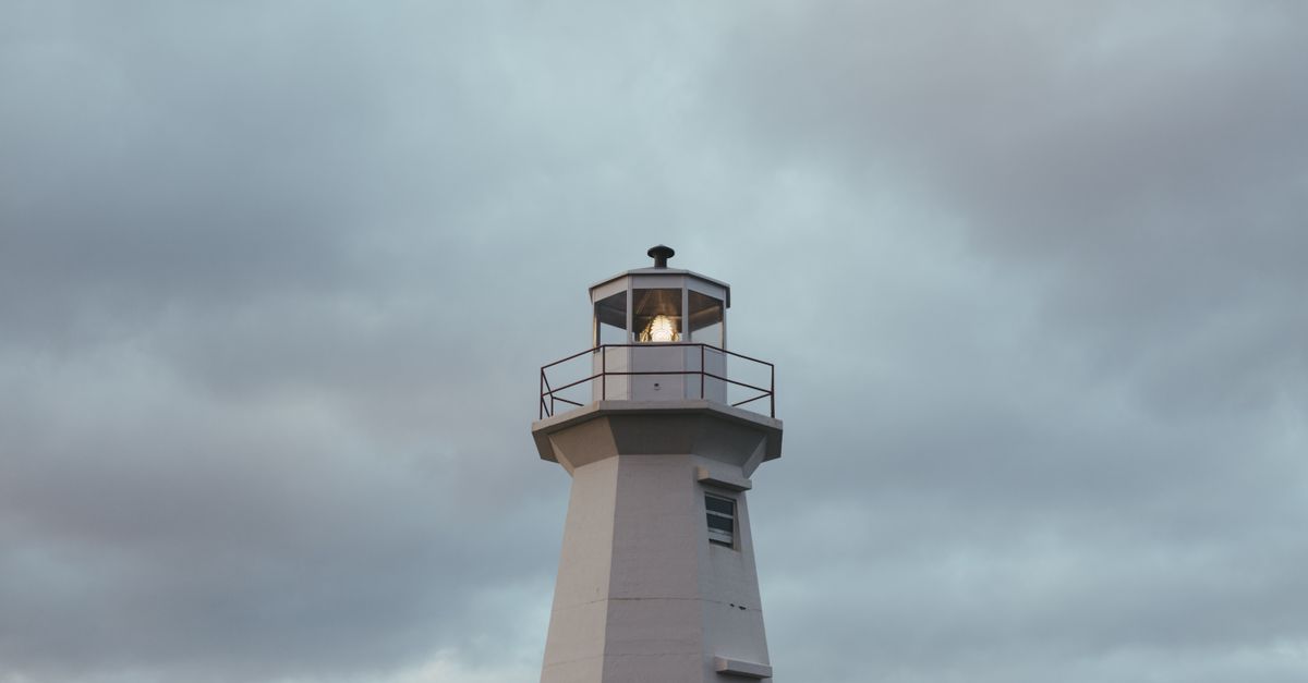 A serene image of a lighthouse standing tall under a cloudy sky, ideal for maritime themes.