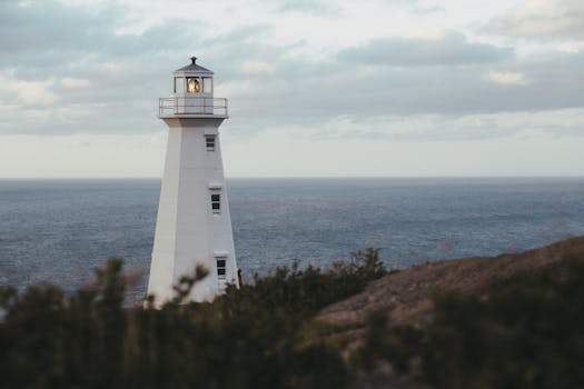 A serene lighthouse standing tall by the ocean under a cloudy sky.