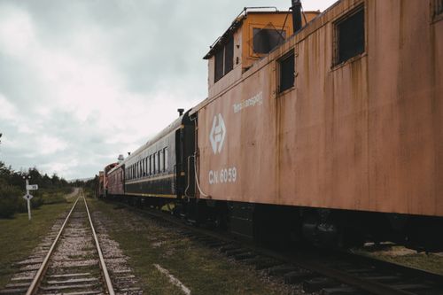 Free Rustic vintage train on railroad tracks on a cloudy day in a scenic outdoor setting. Stock Photo