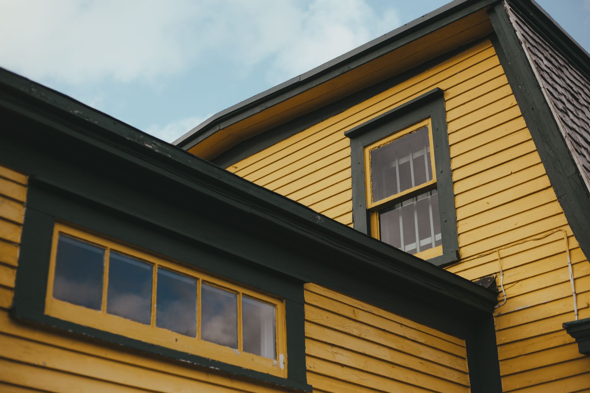 Exterior House Painting Cost in Richfield for 2026 3 Low angle shot of a vibrant yellow house with green trim, featuring classic architecture.