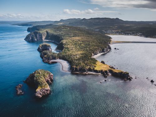 Free Stunning aerial shot of a coastal peninsula with rocky cliffs and lush greenery. Stock Photo