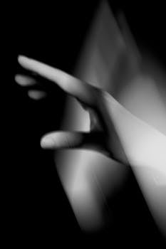 Abstract black and white photo of a hand reaching out, capturing motion and emotion.