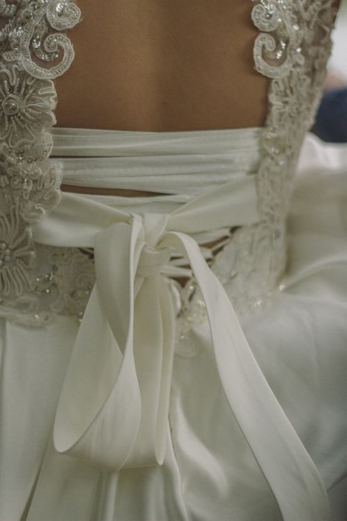 Free Close-up of a wedding dress showcasing intricate lace, elegant ribbons, and delicate beadwork. Stock Photo