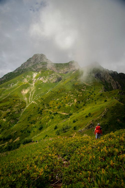 A Person Hiking on Green Mountain Under the Cloudy Sky