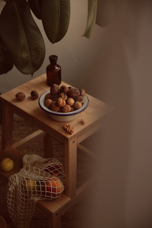 Photograph of a Bowl of Walnuts Beside a Brown Bottle