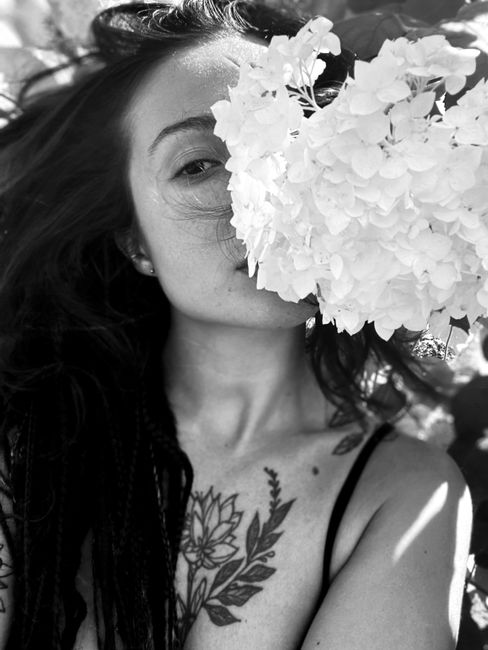 Artistic monochrome portrait of a woman with a flower, showcasing tattoos.