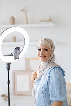 Portrait of a young Muslim woman with ring light indoors for a creative project.