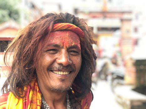 Vibrant portrait of a smiling Hindu Sadhu with face paint in Kathmandu, Nepal.