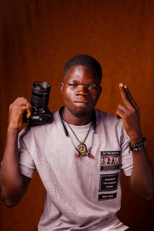 A Man Holding a Camera while Posing