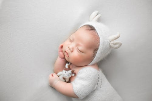 A Cute Baby in White Knitted Cap Sleeping