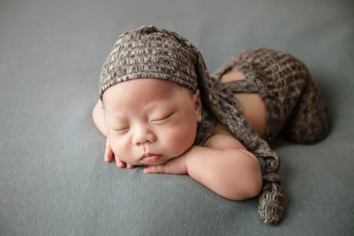 Free A Newborn Baby with Hands on Chin while Sleeping Stock Photo