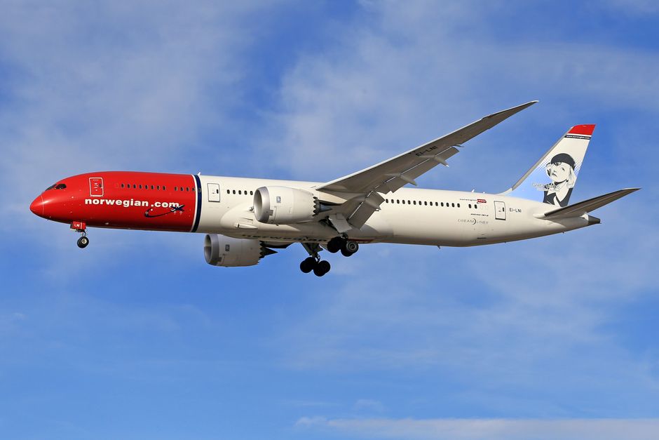 A Norwegian Boeing 787 Dreamliner aircraft flying against a clear blue sky.