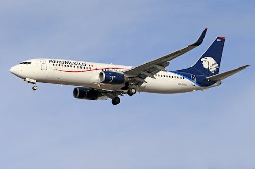 A White and Blue Airplane Flying in the Sky