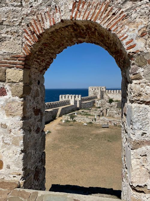 Free Scenic view through a historic castle archway with stone walls and sea backdrop. Stock Photo
