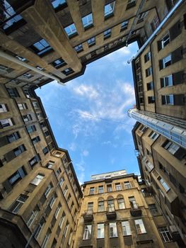 Dramatic upward view of historic urban buildings against a blue sky, showcasing architectural design.