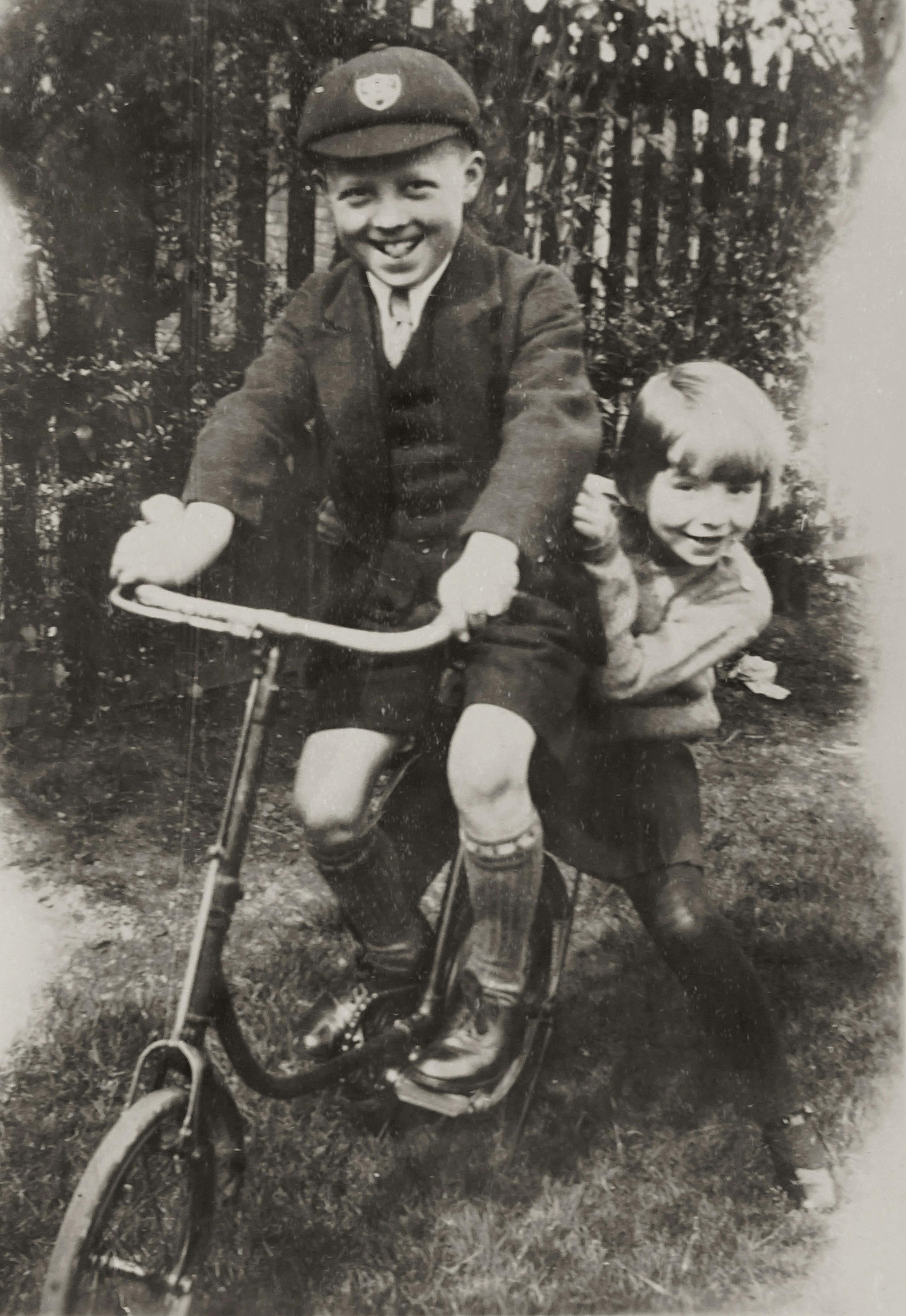 Delightful vintage image of two children on a bicycle, showcasing sibling joy and nostalgia.
