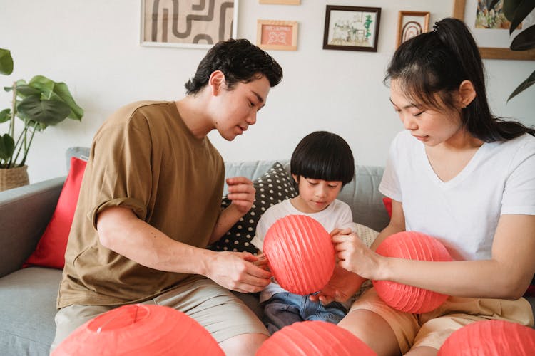 Family Making Red Lanterns On The Couch