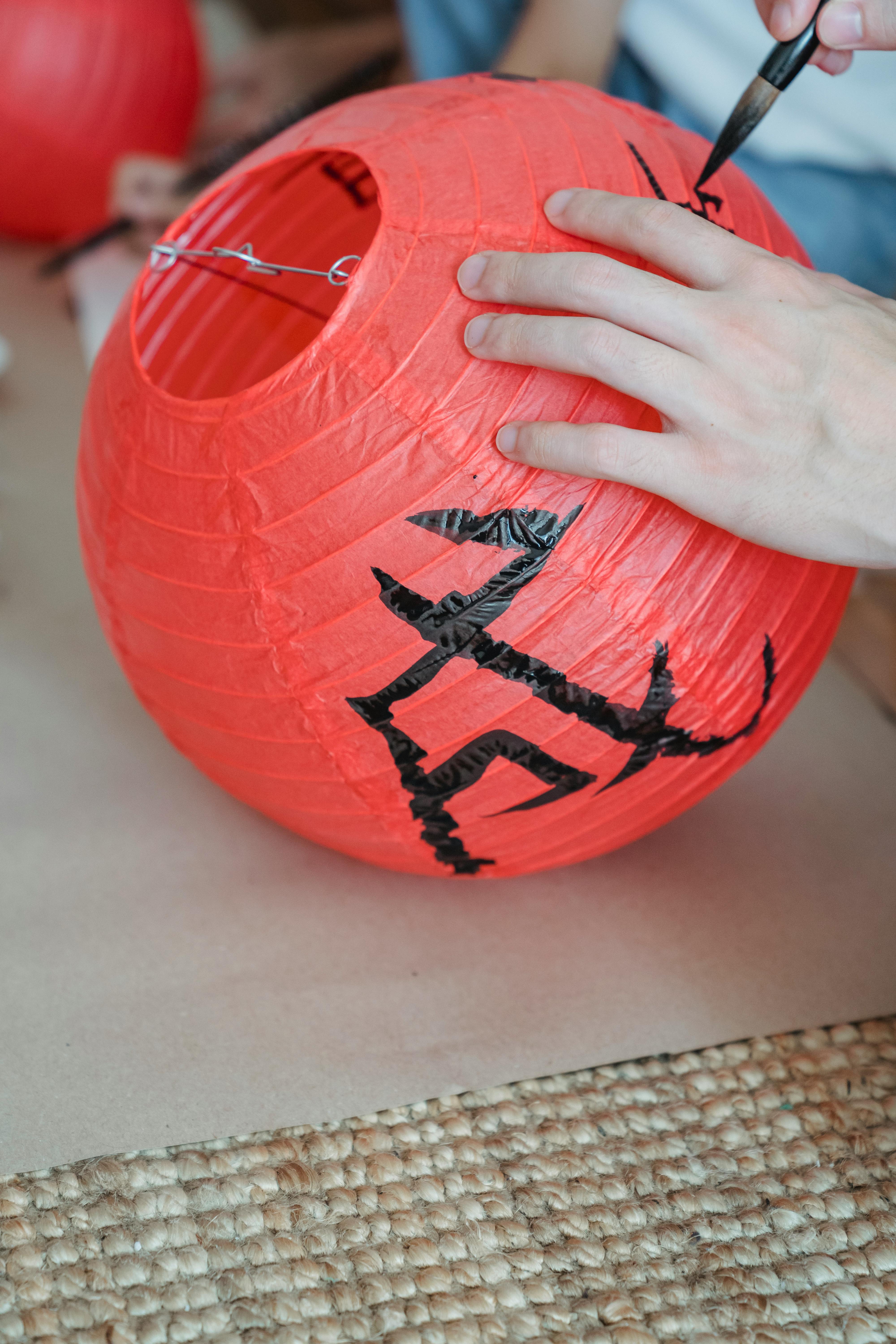 hand of a person writing text with a paint brush on a paper lantern