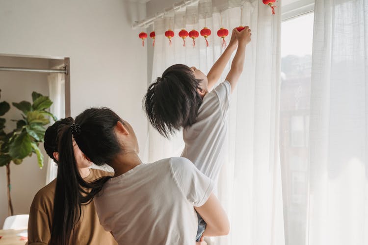 Family Putting Hanging Lanterns On Curtains